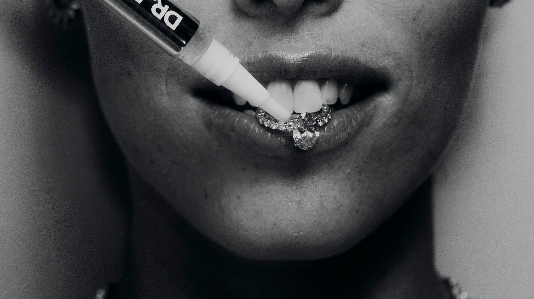 drdiamondcleaningpencleaningdiamondengagementringinmouthofwomaninblackandwhite