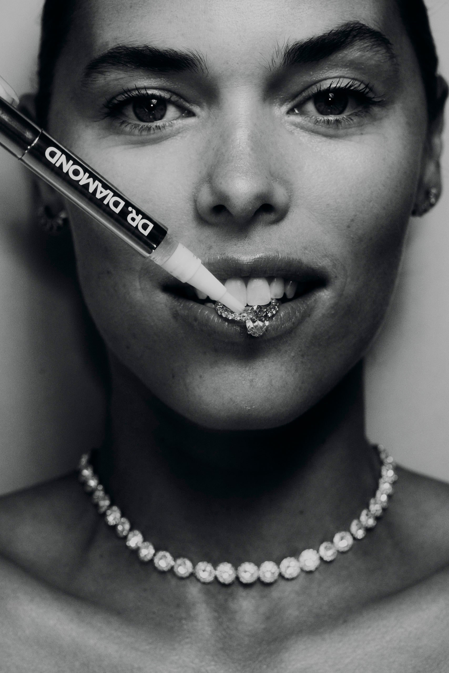 drdiamondcleaningpencleaningdiamondengagementringinmouthofwomaninblackandwhite