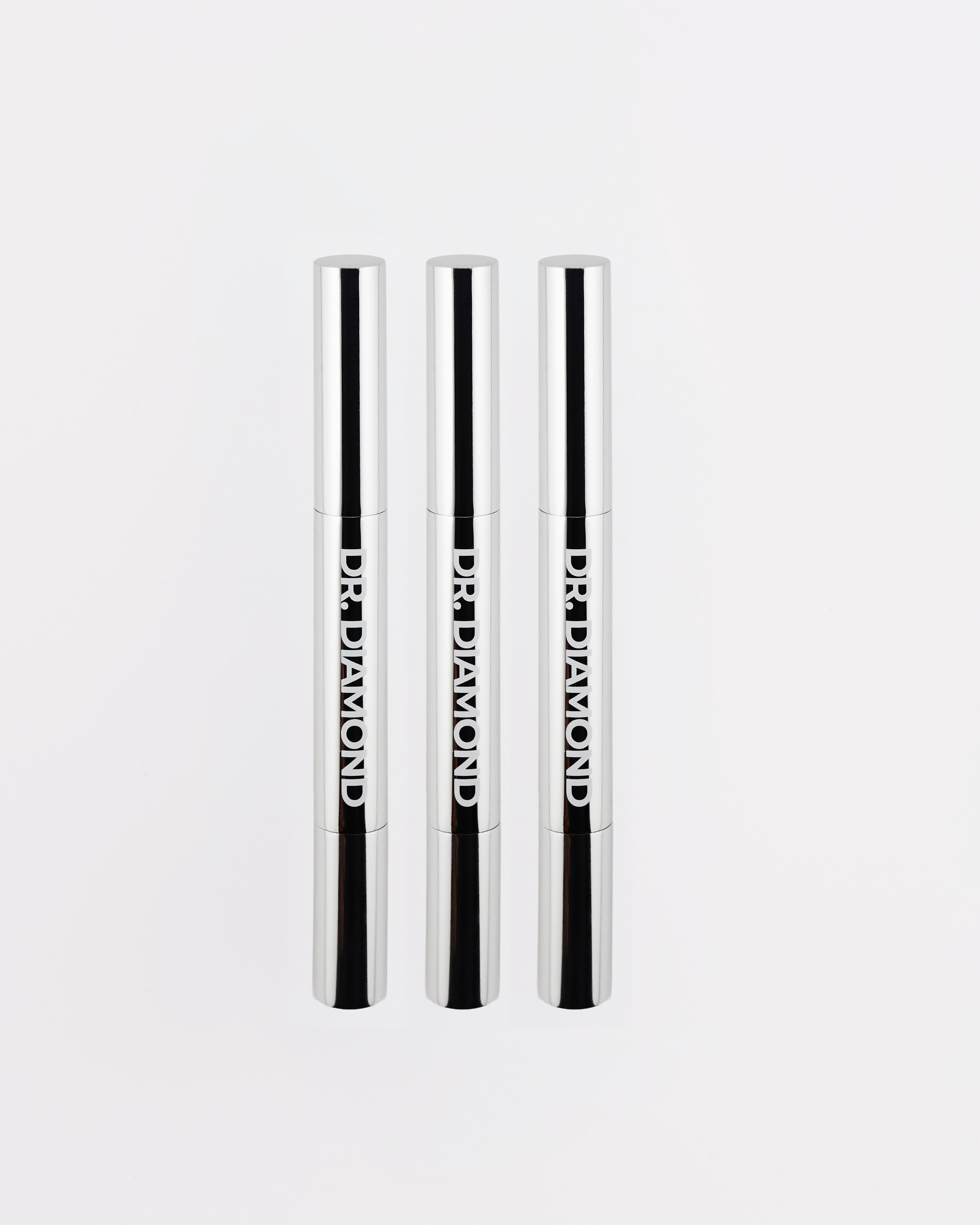 Three black and white cosmetic pencils with brand name on a light gray background